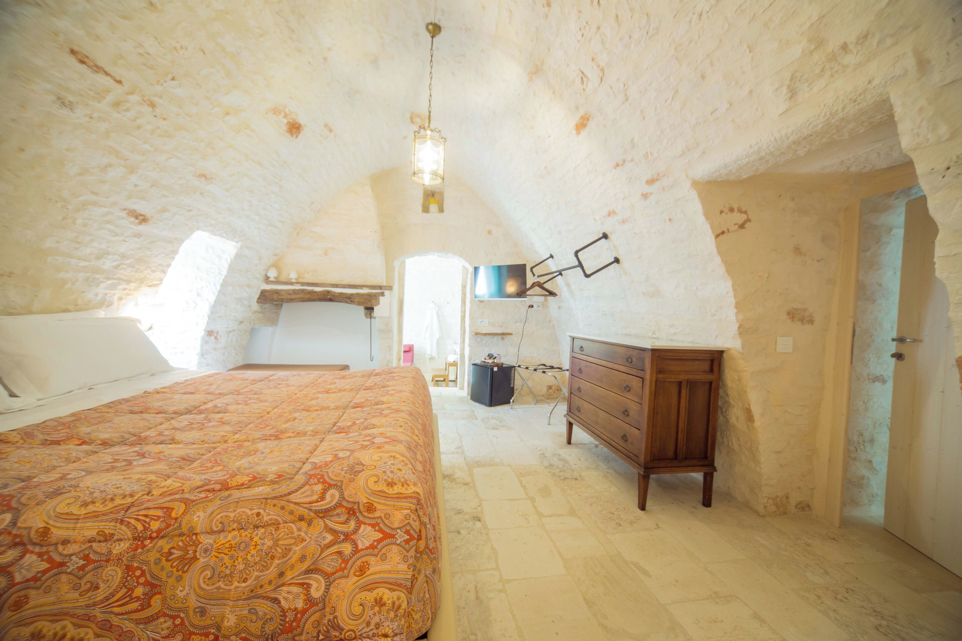 Un dormitorio con una cama grande, un aparador y una lámpara colgante.