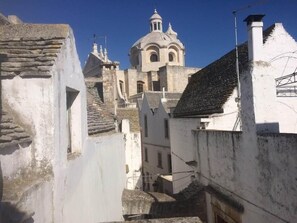 A narrow street with stone buildings and a church with a dome. - Bella Itria (Locorotondo)