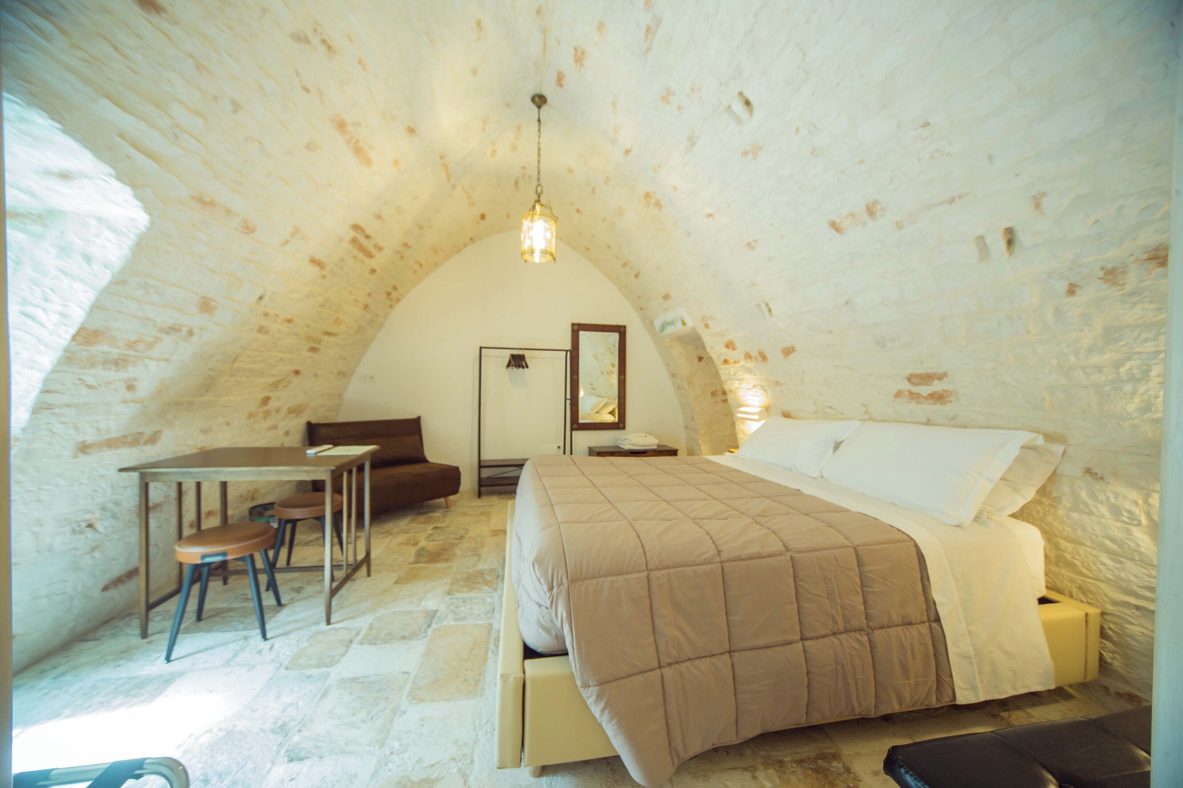 Une pièce confortable, dotée d’une voûte, avec un lit, un bureau et une chaise.