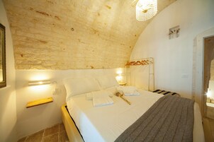 A bedroom with a brick ceiling, a bed with white linens, a wooden bedside table, and a hanging light fixture.