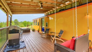 Une terrasse couverte avec un barbecue, des chaises et une balançoire.