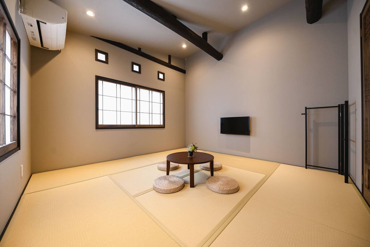 Ein Raum mit Tatami-Matten, einem Tatami-Tisch, einer kleinen Pflanze und einer Schiebetür.