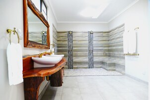 A bathroom with a wooden vanity, two sinks, a large mirror, and a shower area with a glass door.