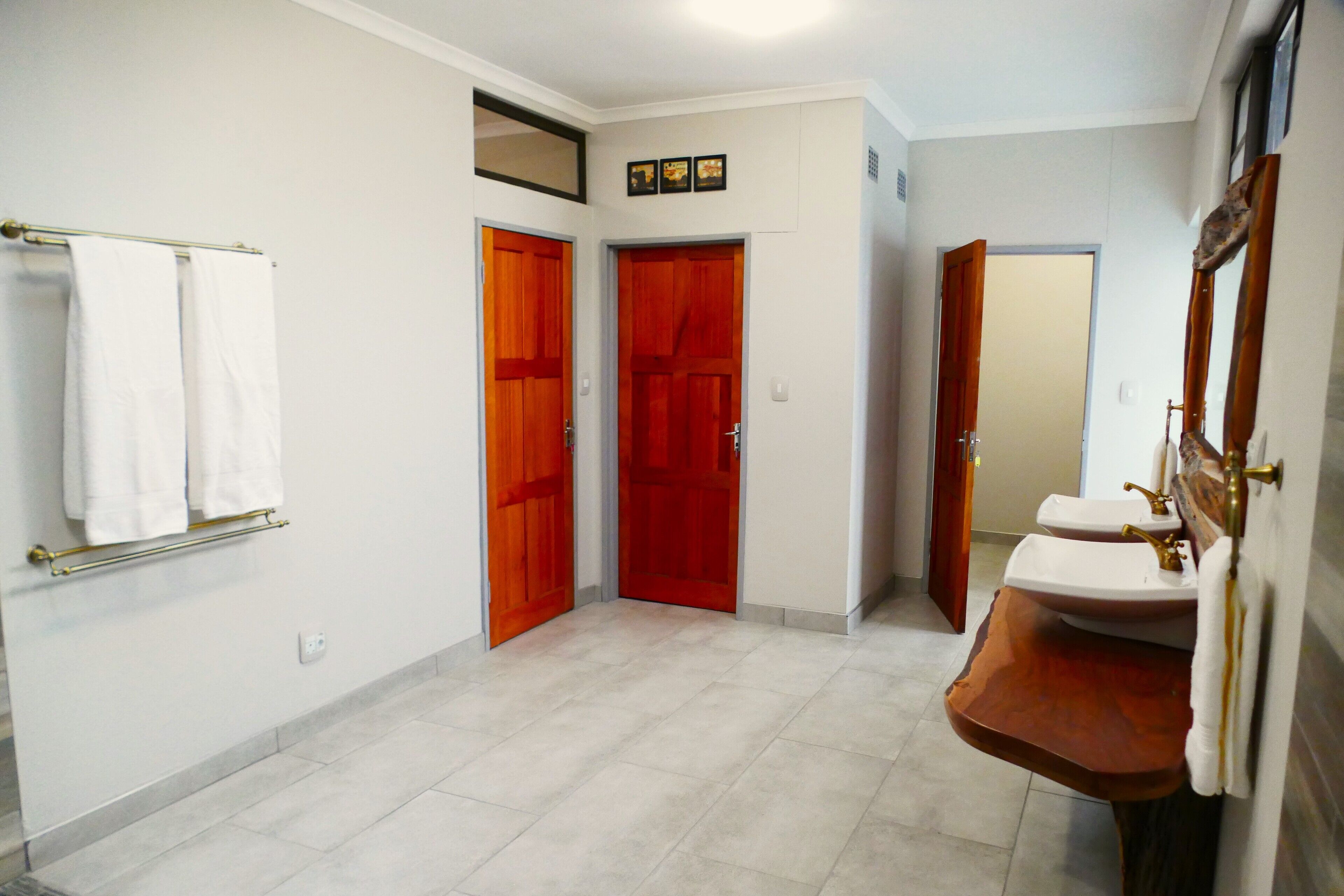 A bathroom with two sinks, a towel rack, and two wooden doors.
