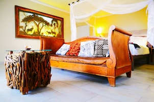 A room with a wooden sofa, a glass coffee table, and a unique carved stool.
