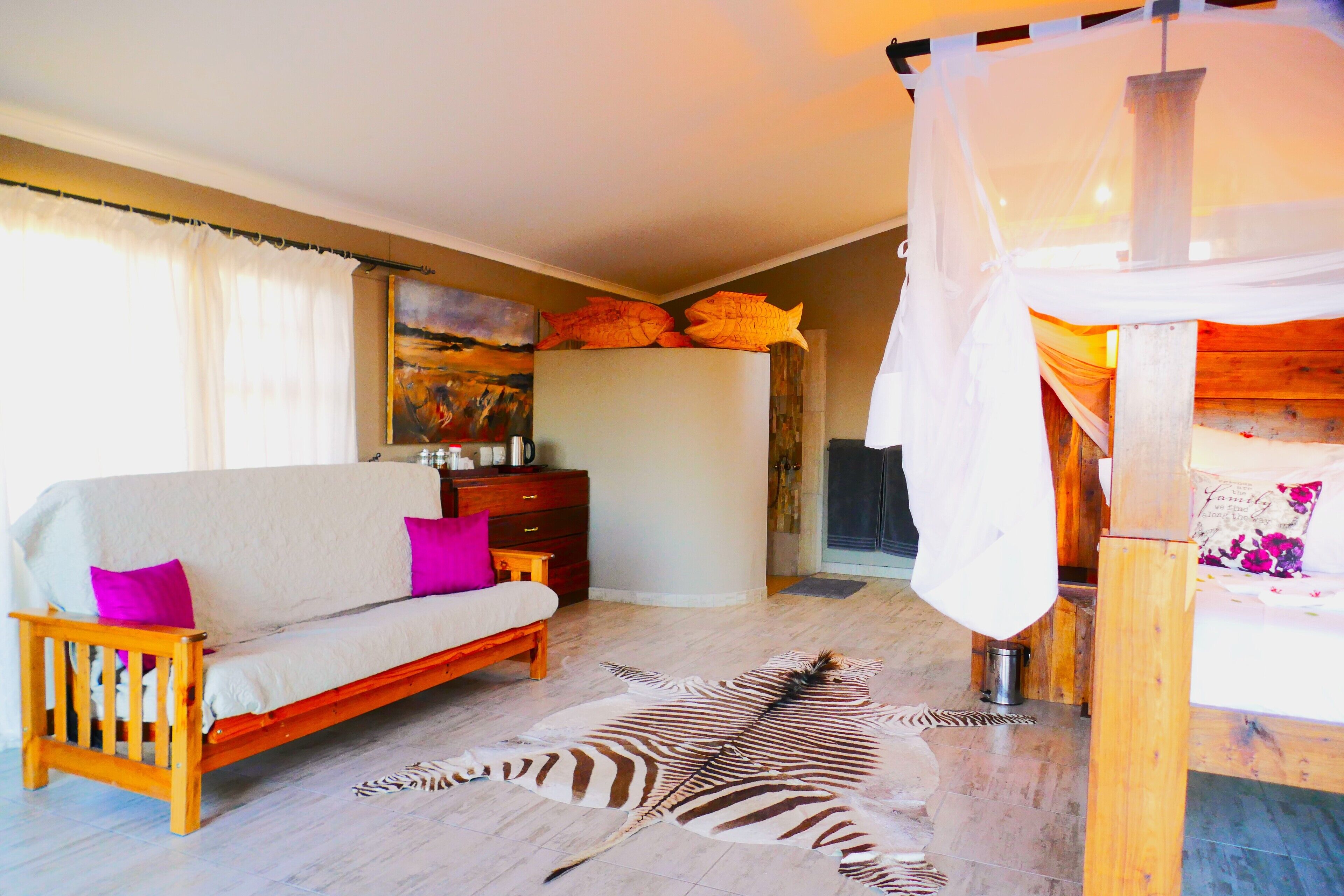 A room with a sofa, a zebra rug, a wooden bed, and a painting on the wall.