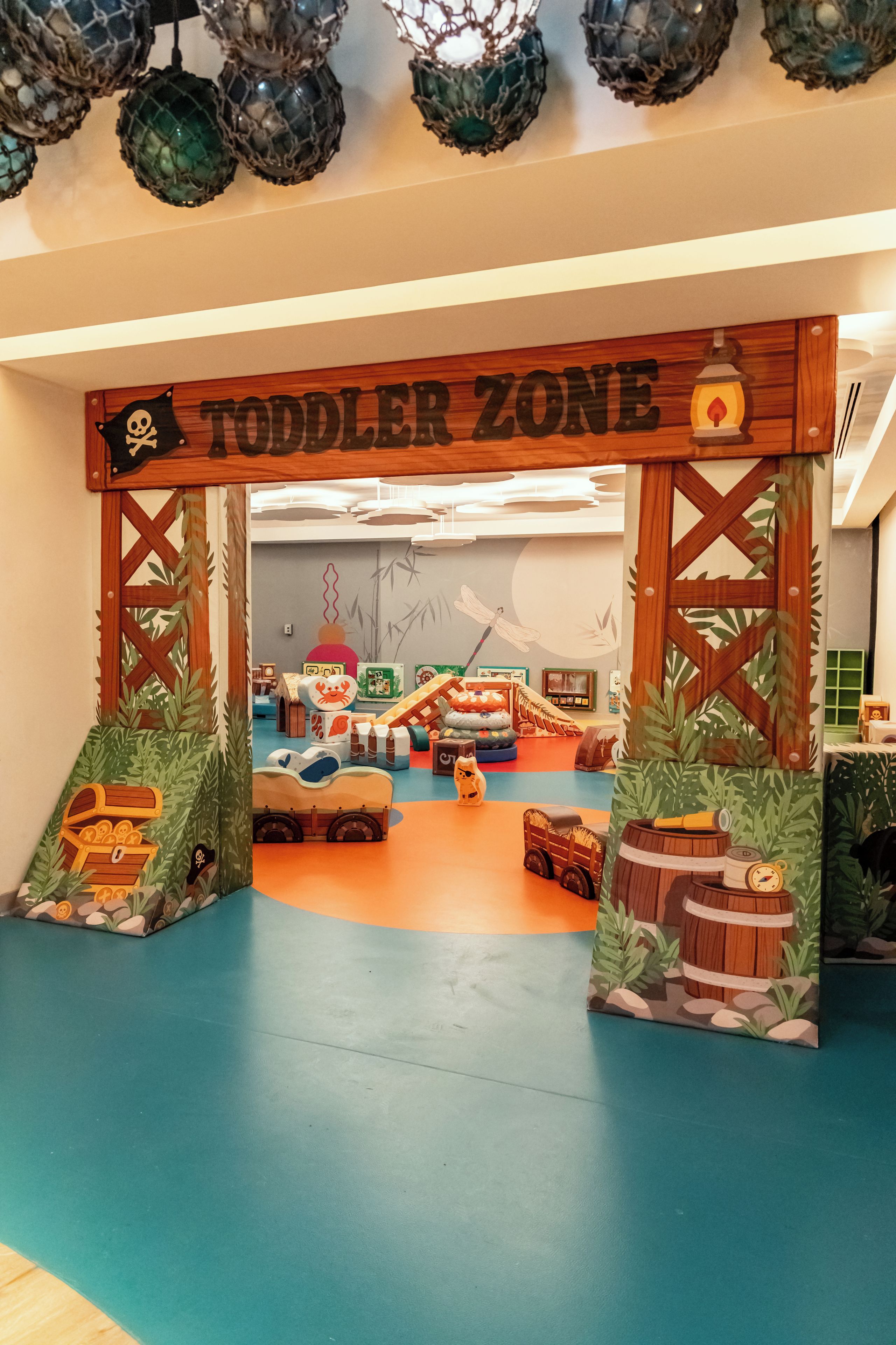 Ein Spielbereich für Kleinkinder mit einer hölzernen Torbogen, Spielgeräten und einer bunten Spielecke.