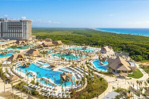 Ein Resort mit mehreren Schwimmbecken, einem großen Gebäude und Blick auf den Ozean.