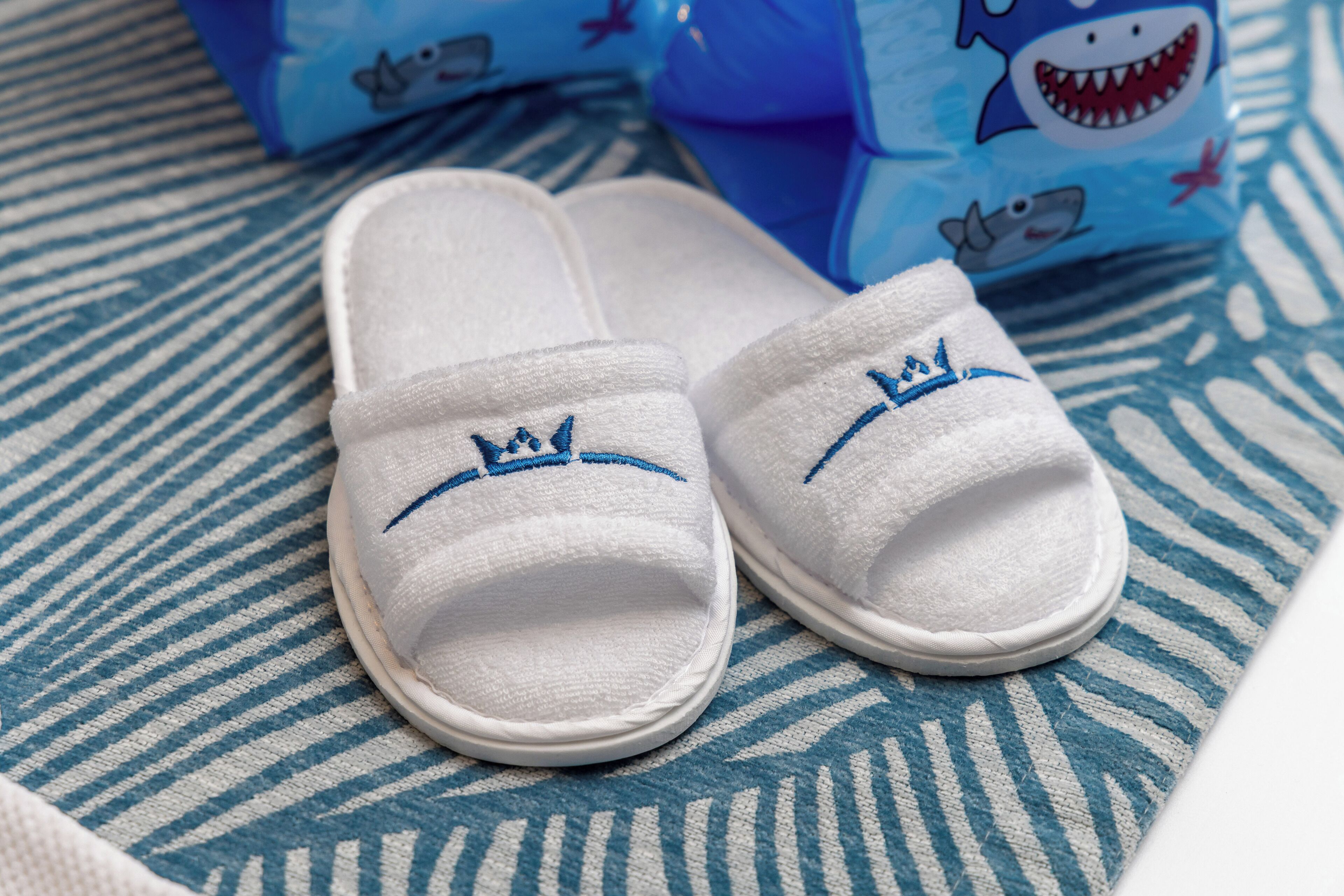 Un paio di pantofole bianche con ricami blu su un tessuto decorato.