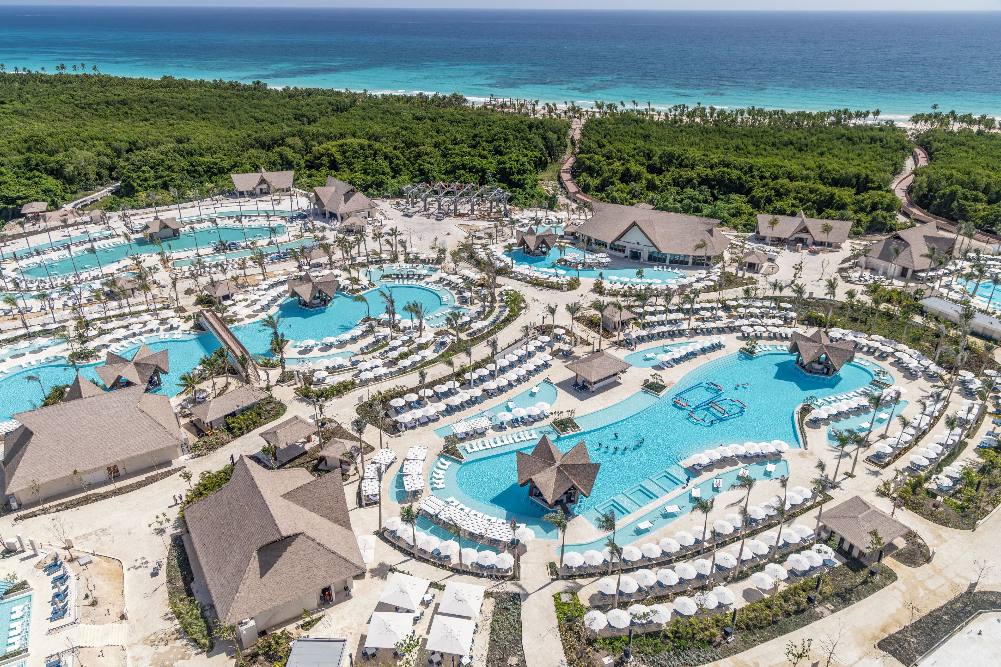 Un complexe hôtelier doté de plusieurs piscines, d’espaces de plage et de palmiers.