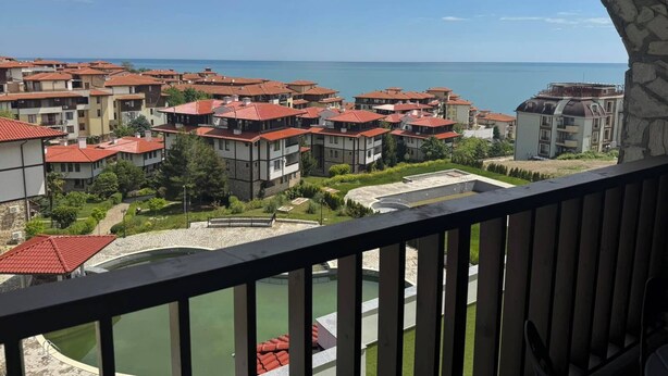 A coastal residential area with multiple apartment buildings, a swimming pool, and a view of the sea.