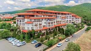 A multi-story hotel with a red-tiled roof, surrounded by greenery and a parking lot.