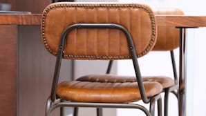 A chair with a padded seat and back, metal frame, and decorative stitching. - Studio37 - A cosy, stylish central hideaway | Pass the Keys (Cirencester)