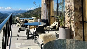 Un balcone con tavolo e sedie, un riscaldatore e piante in vaso.