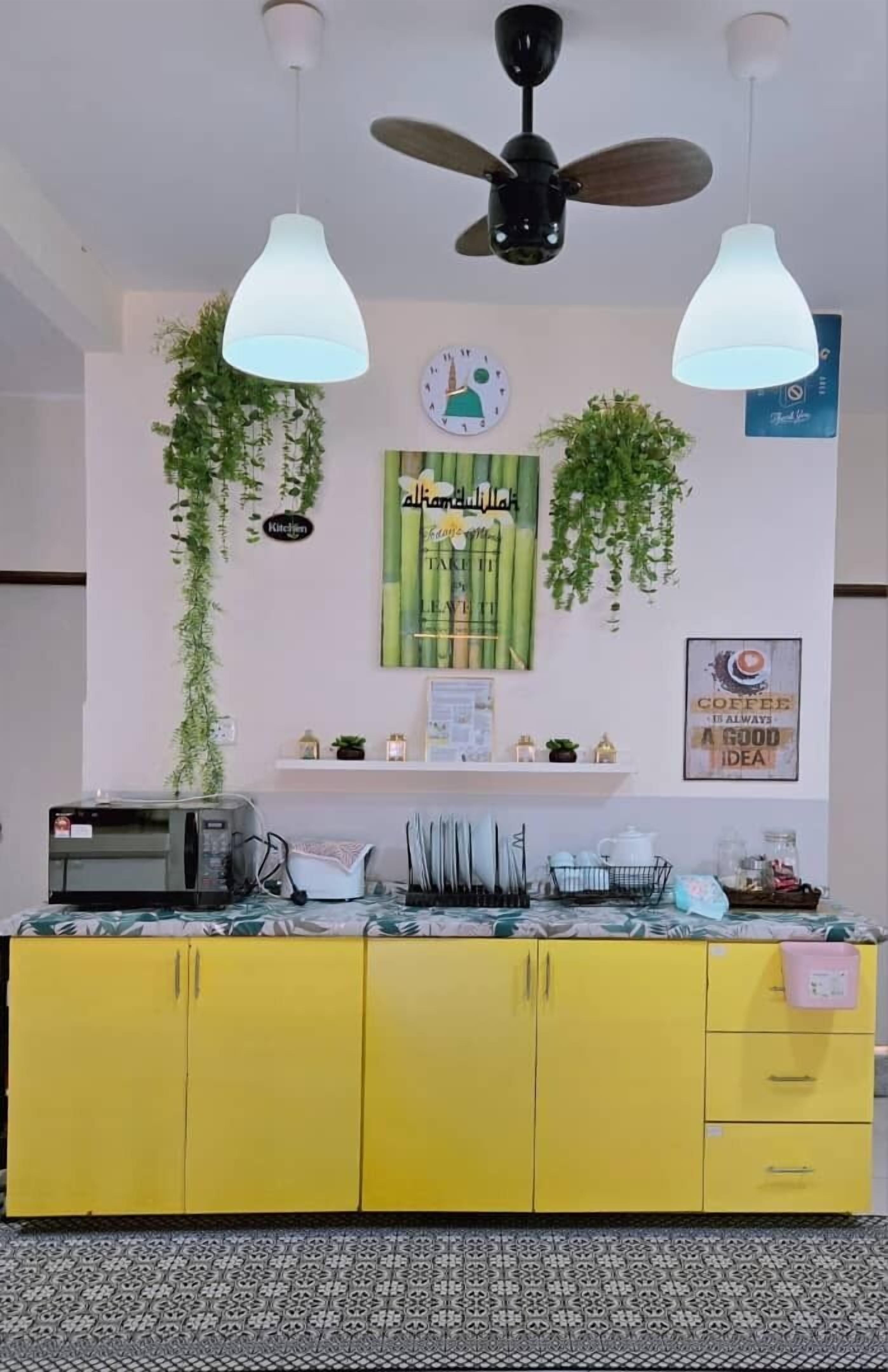 A yellow kitchen with a ceiling fan, pendant lights, and wall-mounted plants.