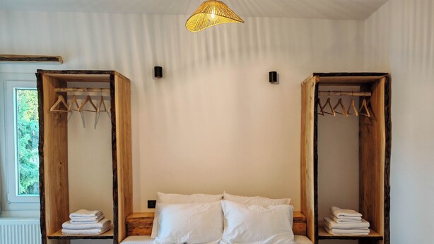 Une chambre avec un grand lit, une tête de lit en bois et un luminaire suspendu.