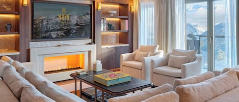 A modern living room with a fireplace, comfortable seating, and a large window offering a mountain view.