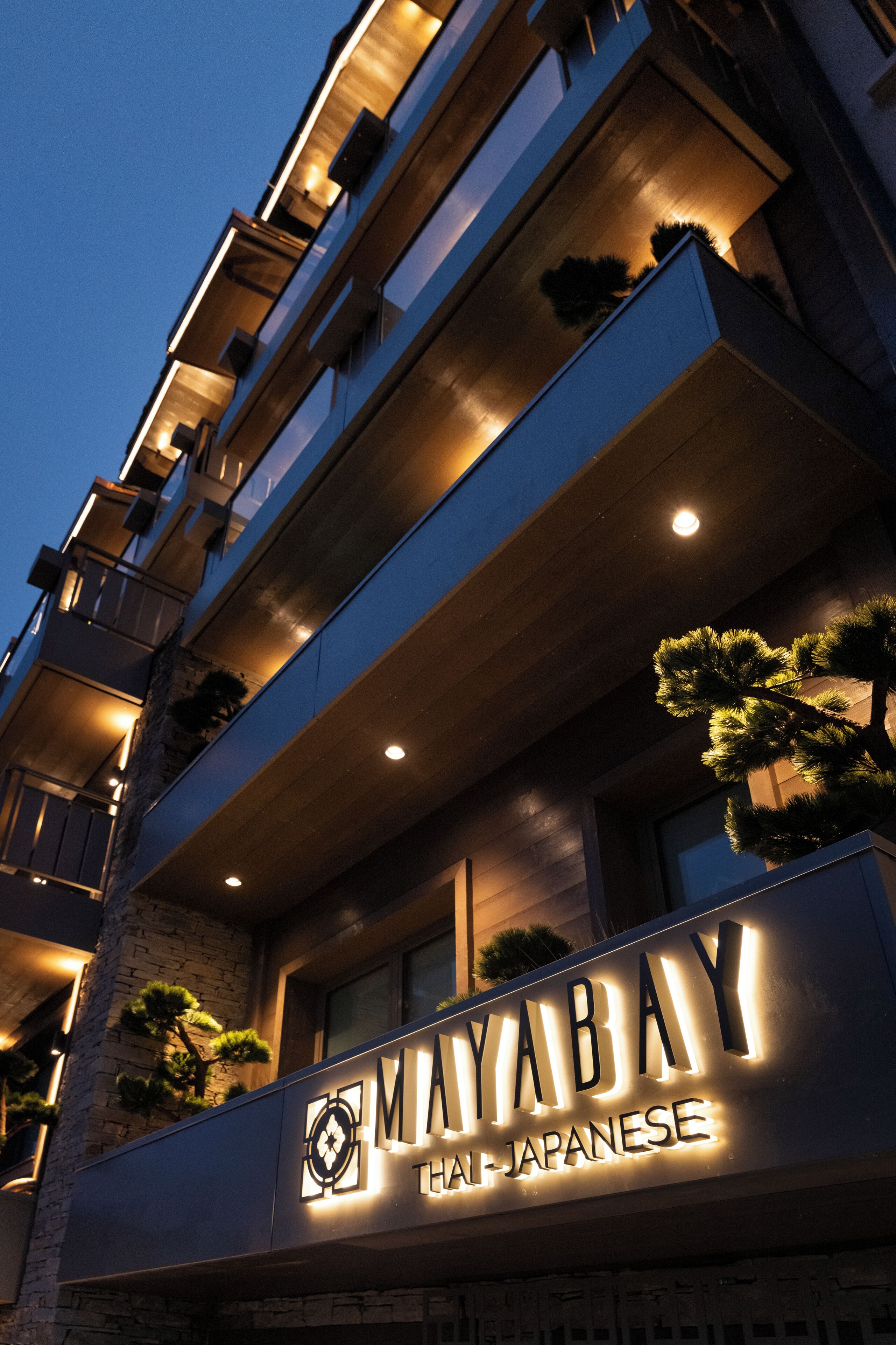 Un hotel de varios pisos con letreros iluminados que dicen 'Mayabay Hal-Japanese'.