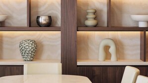 Ein modernes Interieur mit einem Marmortisch und Stühlen, Holzregalen mit Dekoration und einer besonderen Deckenleuchte.