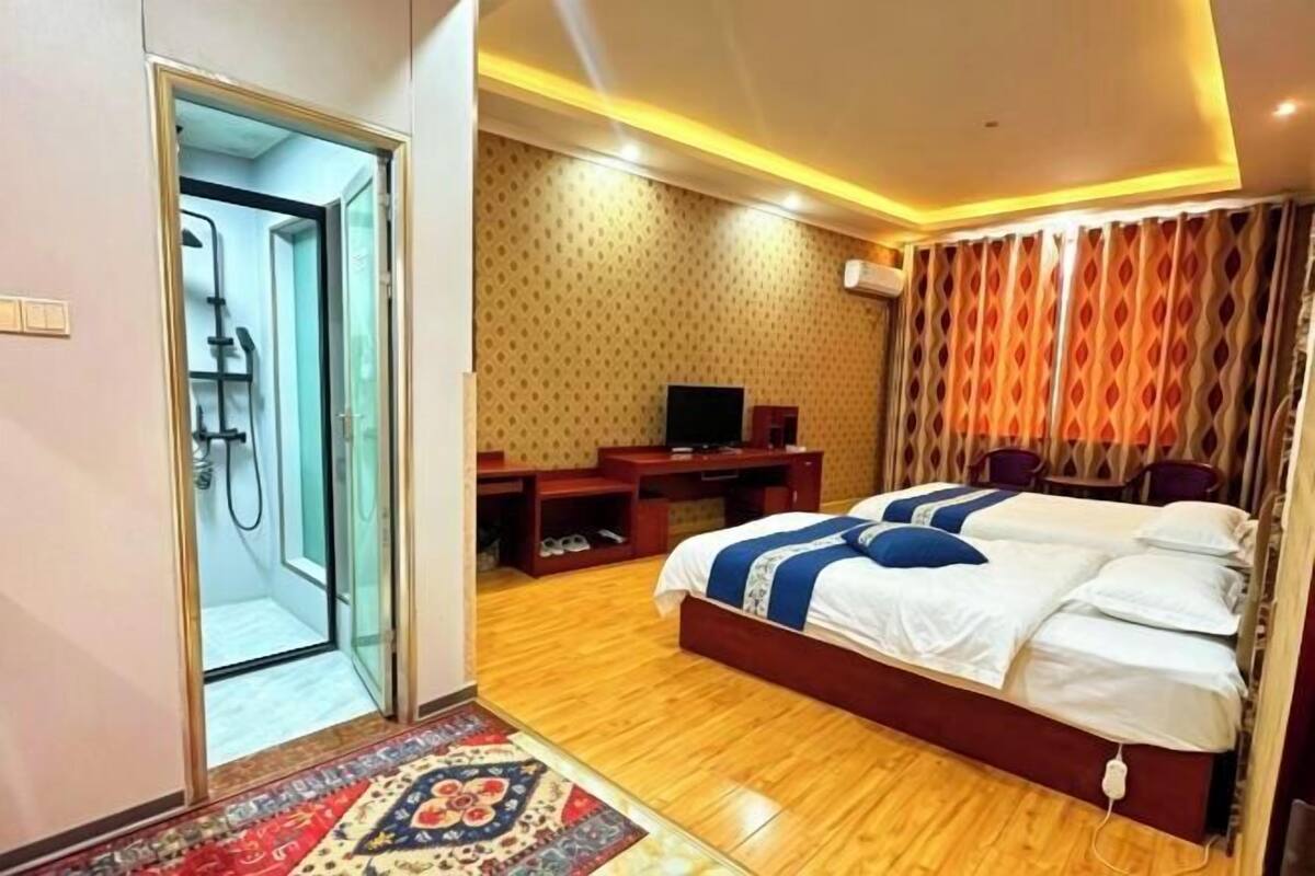 Quarto de hotel com cama, televisão, escrivaninha e chuveiro.