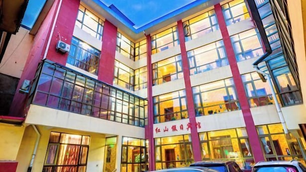 A multi-story building with large windows and a red and white facade. - Luqu Langmusi Hongshan Holiday Hotel (Luqu)