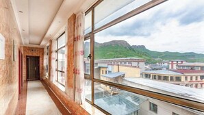 A corridor with large windows and a view of buildings and mountains. - Luqu Langmusi Hongshan Holiday Hotel (Luqu)