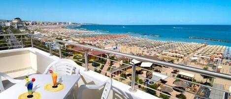 Un balcón con mesa y sillas que da a una playa y al paisaje urbano.