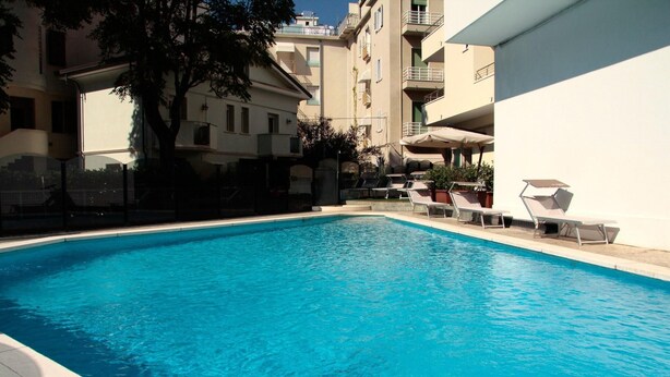 A swimming pool with lounge chairs and a building in the background.