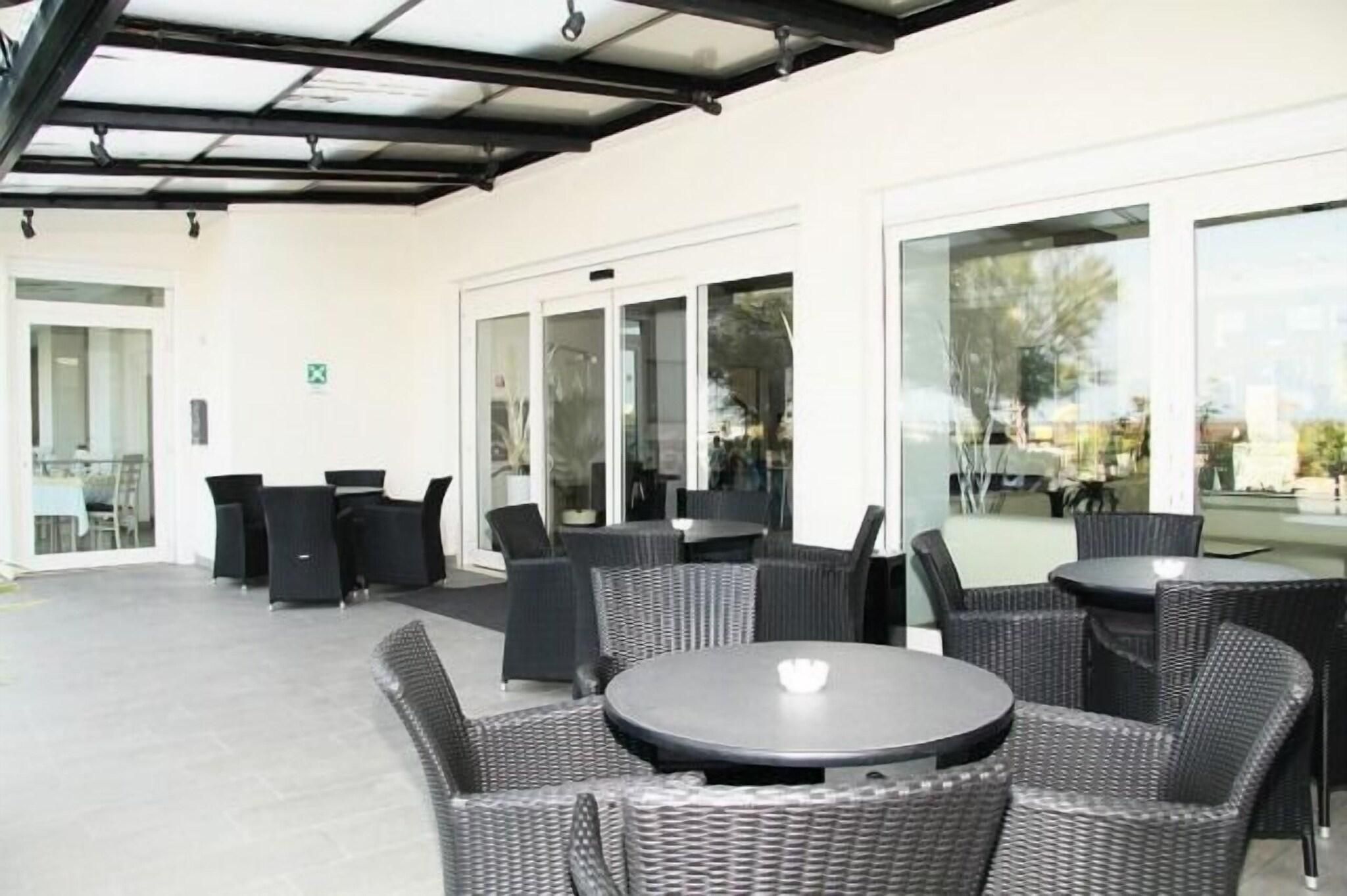A covered outdoor seating area with wicker furniture and glass doors leading to an interior space.