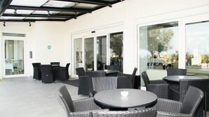 A covered outdoor seating area with wicker furniture and glass doors leading to an interior space.