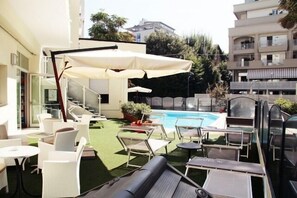 A rooftop pool area with outdoor seating and a view of surrounding buildings.