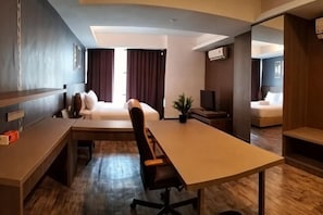 A hotel room with a bed, a desk, a chair, a television, and a small table.
