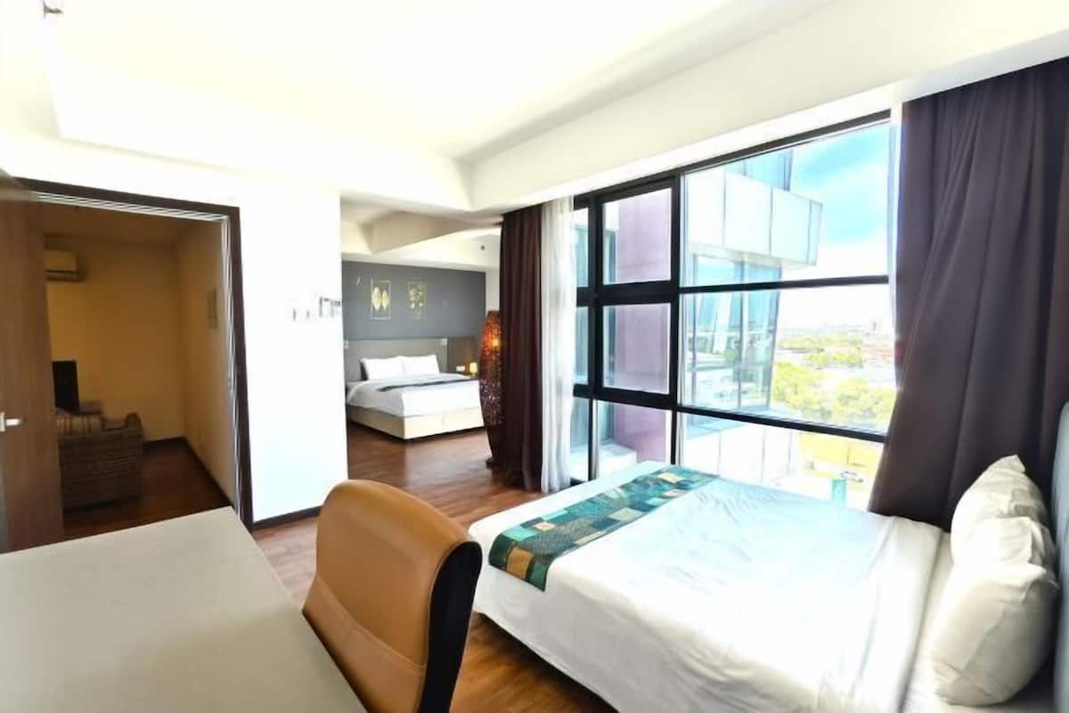 A hotel room with a bed, a desk, a chair, and a large window offering a view.