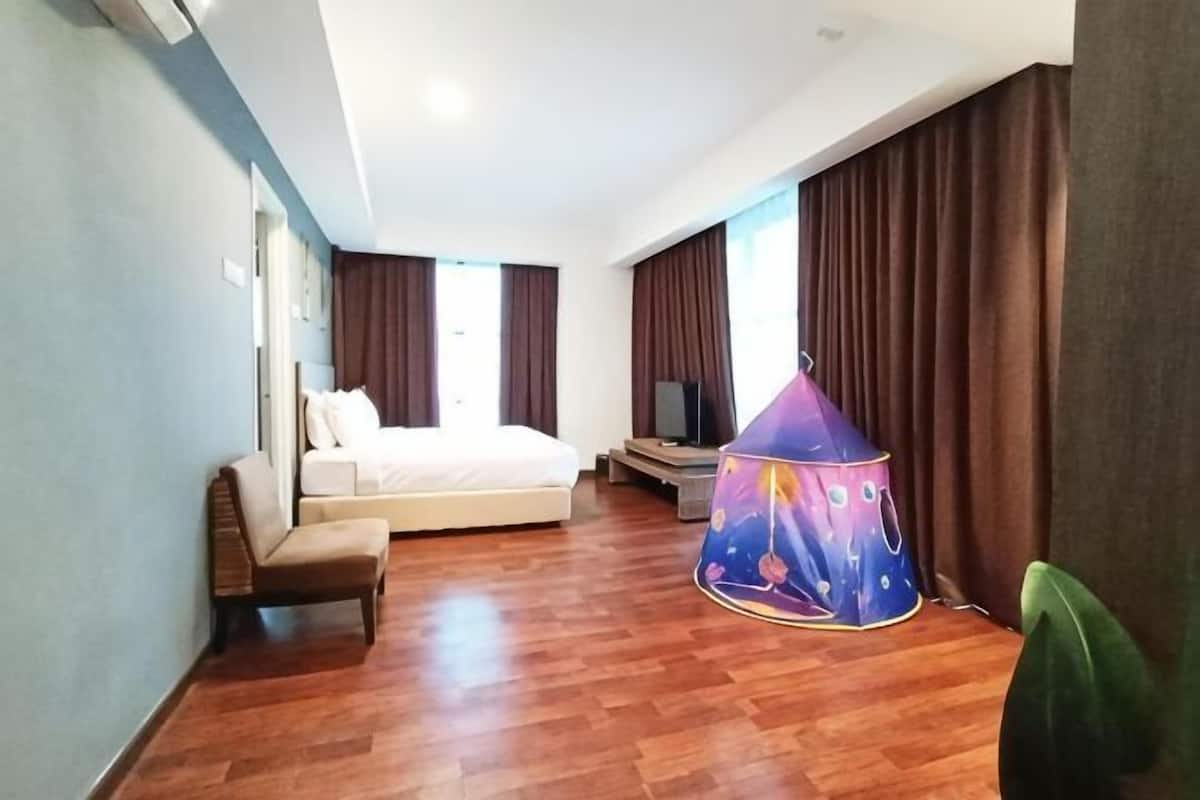 A hotel room with a bed, a chair, a television, and a tent-like structure.
