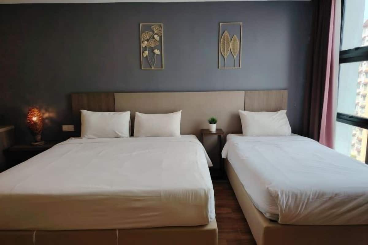A hotel room with two beds, a nightstand with a lamp, and framed artwork on the wall.