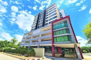 A multi-story building with a modern architectural design, featuring a prominent entrance with a covered area and a flagpole. - Salaam Suites Shah Alam (Shah Alam)