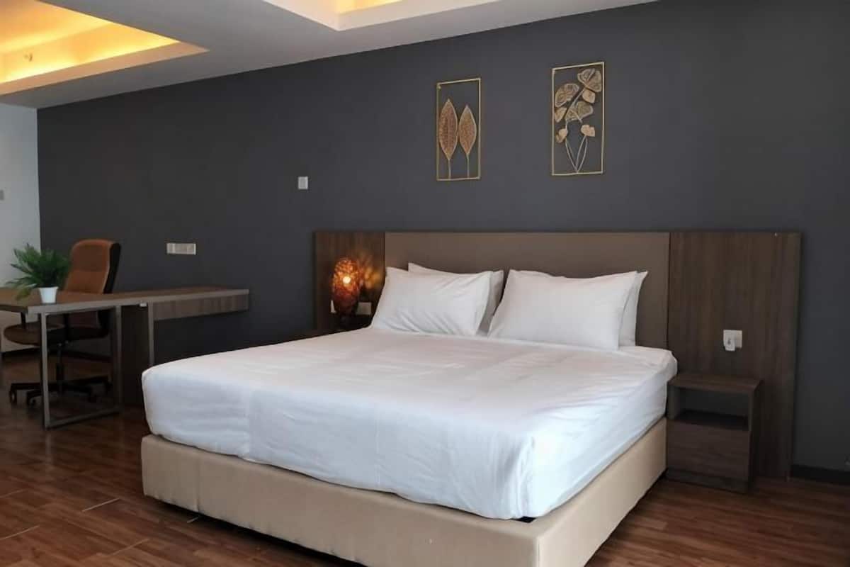 A modern bedroom with a large bed, a desk, and a chair.