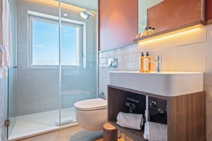 A modern bathroom with a glass-enclosed shower, a white toilet, and a vanity with a mirror and storage.