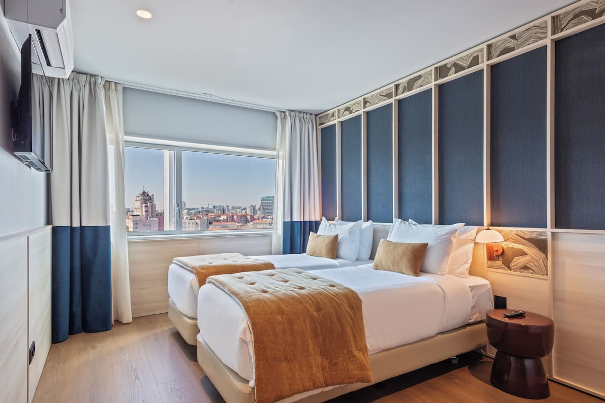 A hotel room with two beds, a large window with curtains, a city view, and a wall with a decorative panel.