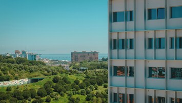 Ένα σύγχρονο κτίριο με πολλά παράθυρα και θέα σε μια γέφυρα και σε καταπράσινο περιβάλλον στο βάθος.
