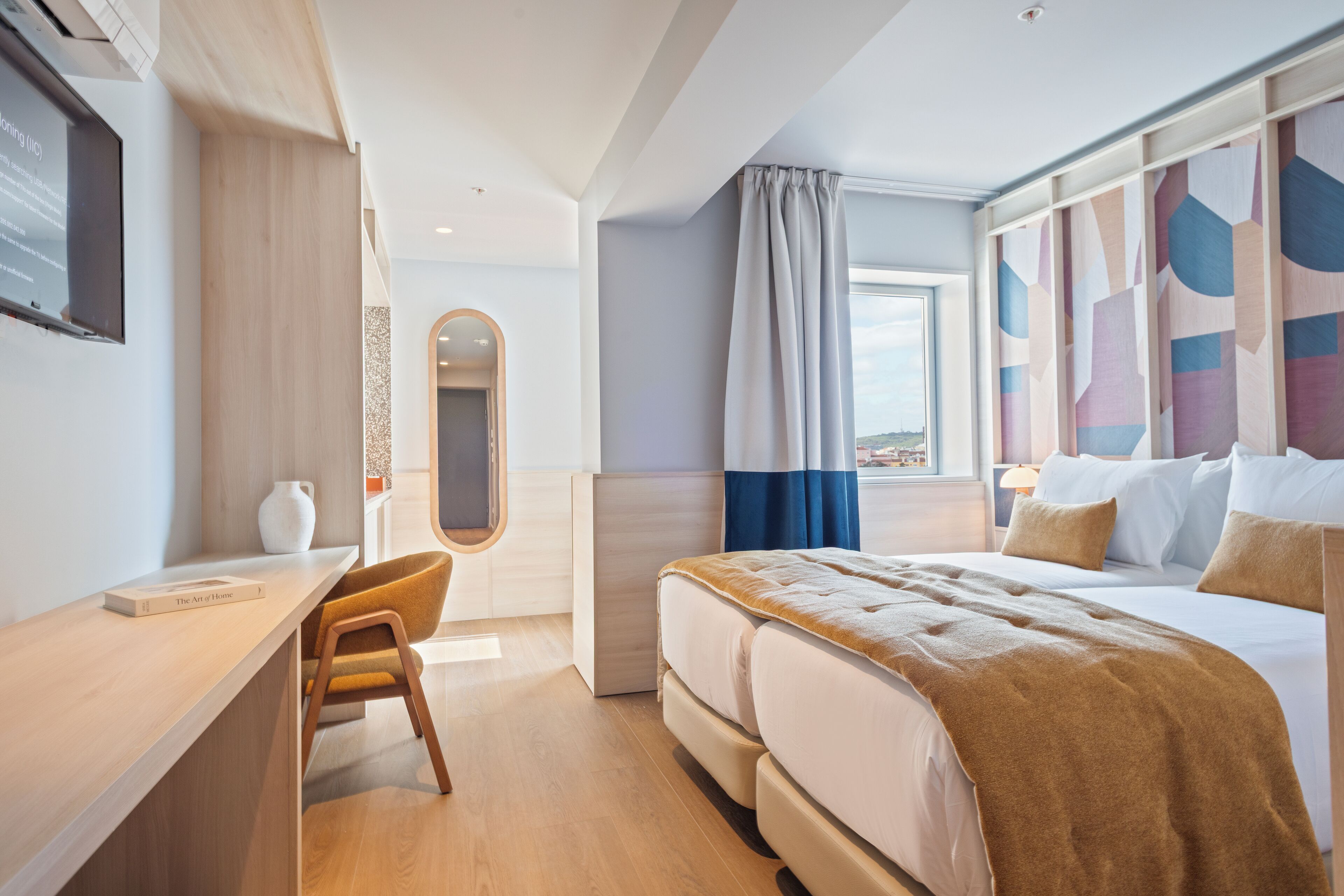 Et moderne hotelværelse med en stor seng, et skrivebord og en stol.