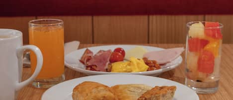 A breakfast setting with a plate of pastries, a glass of orange juice, and a glass of fruit salad.