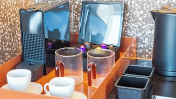 Een koffiehoek met een koffiezetapparaat, twee schermen en een prullenbak.
