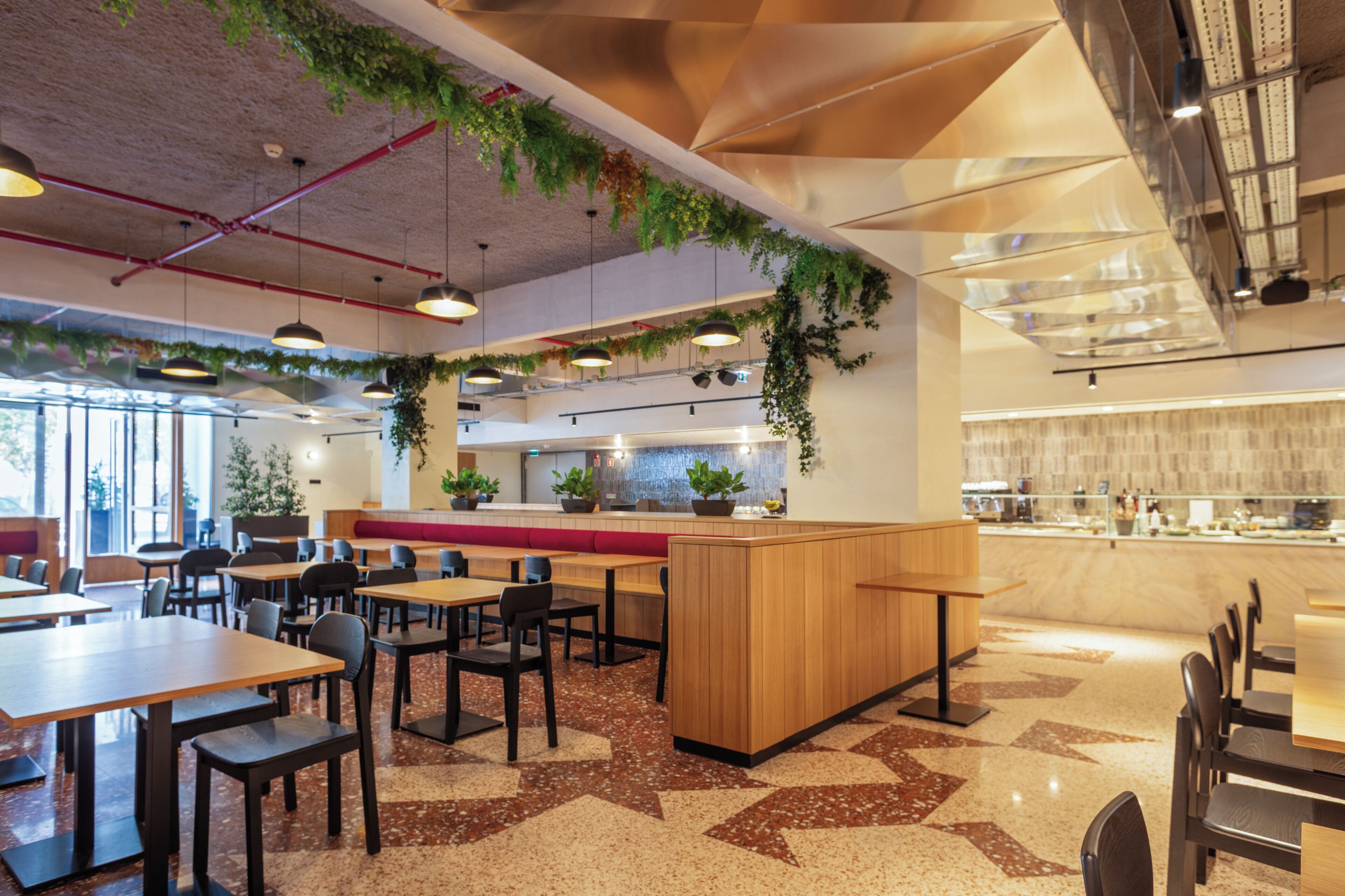 A modern restaurant interior with multiple dining tables, booths, and a kitchen area.