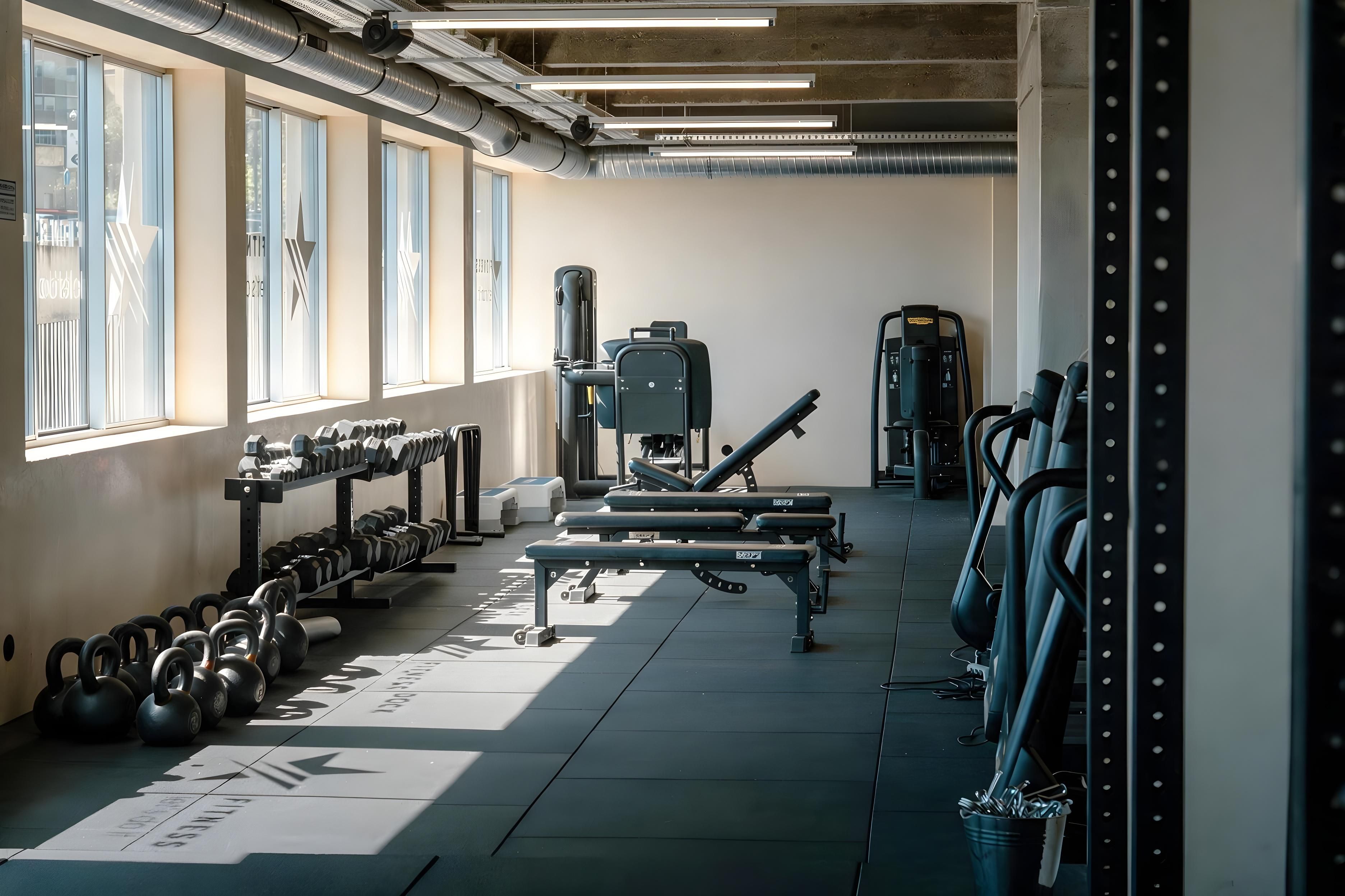 A gym with weightlifting equipment, treadmills, and dumbbells.
