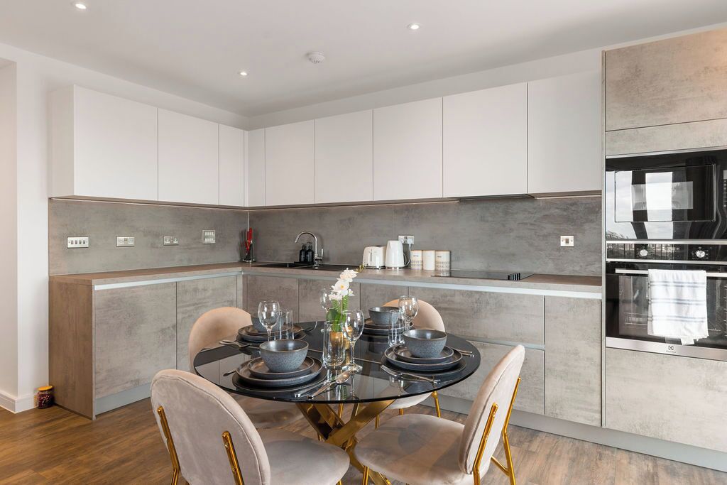 A modern kitchen with a central island, white cabinetry, and a built-in oven.
