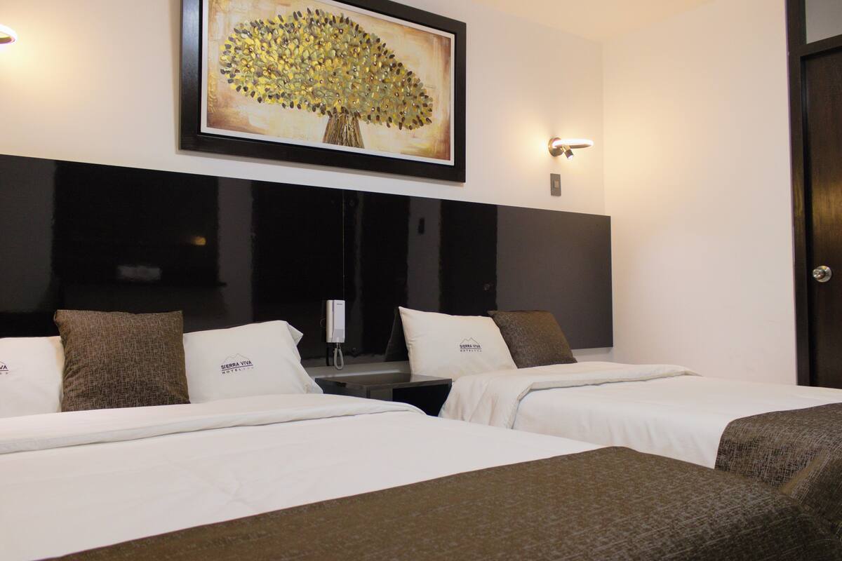 Una habitación de hotel con dos camas, un cuadro de un árbol y un minibar.