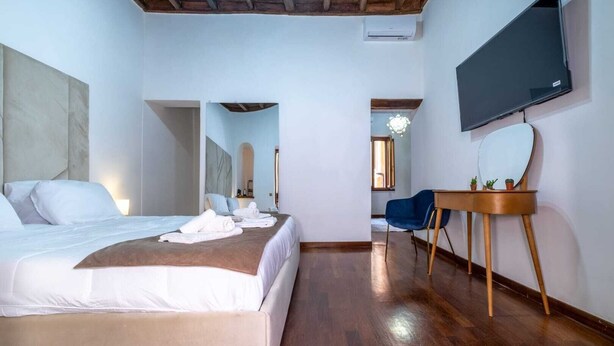 A hotel room with a bed, a desk, a chair, a TV, and a mirror.