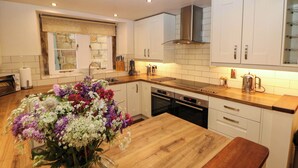 Una cocina moderna con armarios blancos, encimera de madera y horno empotrado.