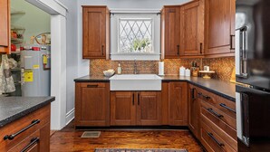 A kitchen with wooden cabinets, a stainless steel refrigerator, a window with a diamond pattern, and a tiled backsplash. - 3 bed/2 BA house in great Augusta area w/Wi-Fi, AC, and many restaurants nearby (Augusta)